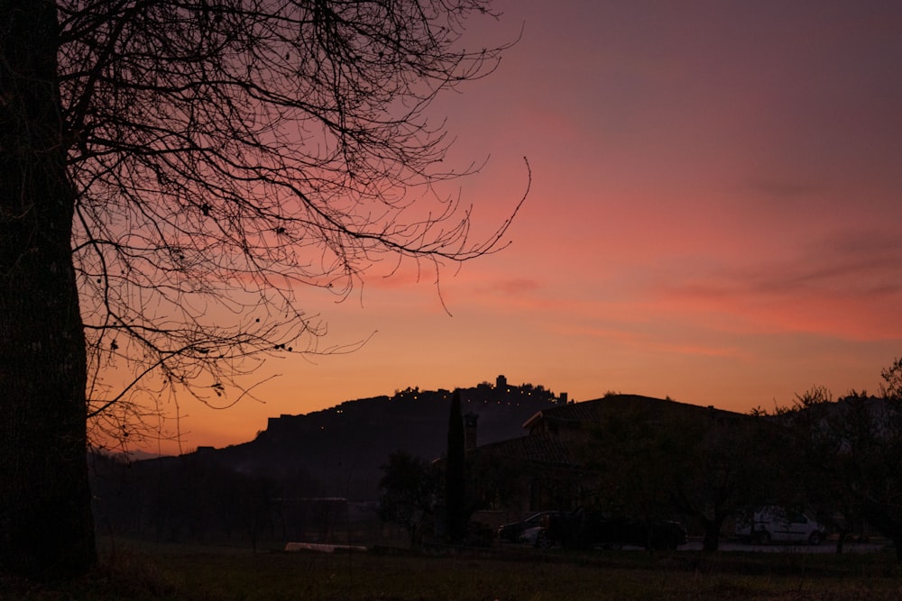 the sun is setting behind a hill and trees