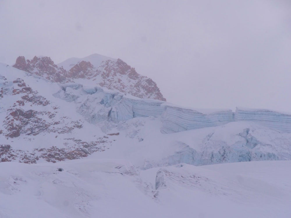 a mountain covered in snow with a snowboarder in the foreground