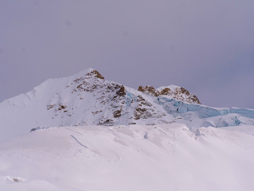 a mountain covered in snow with a sky background