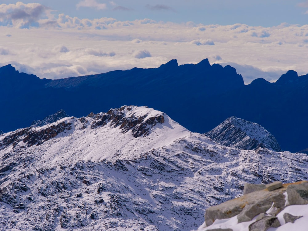 a snow covered mountain with a few clouds in the sky