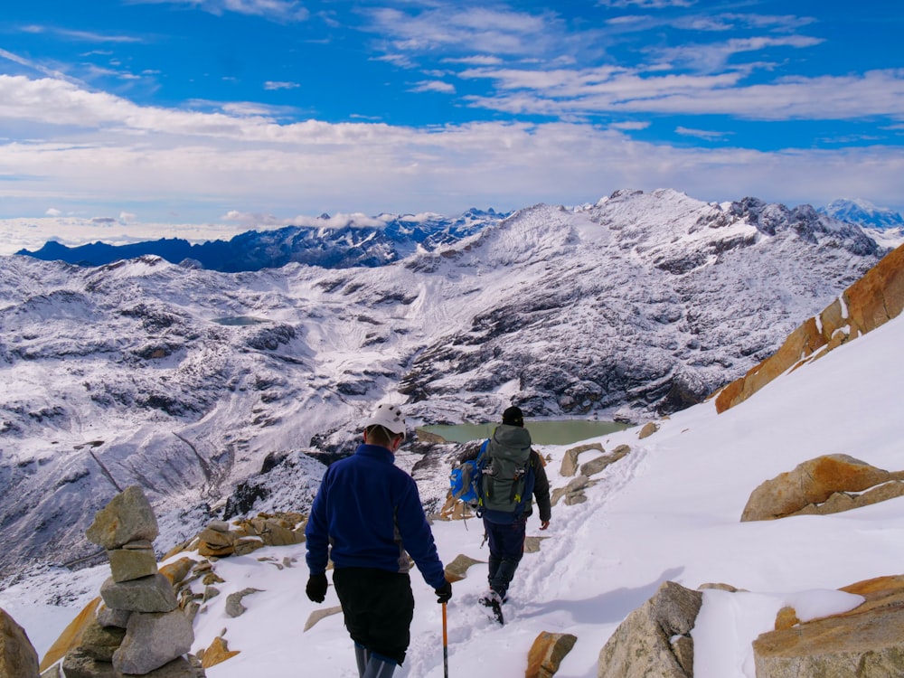 a couple of people walking up a snow covered slope