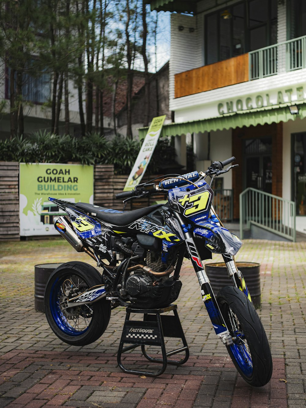 a blue and yellow dirt bike parked in front of a building
