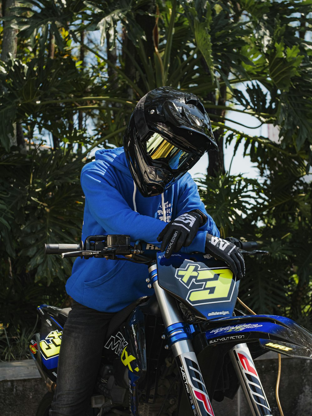 a man in a blue jacket and helmet sitting on a dirt bike
