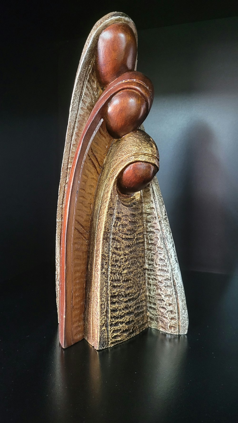 a wooden sculpture of a person holding a book