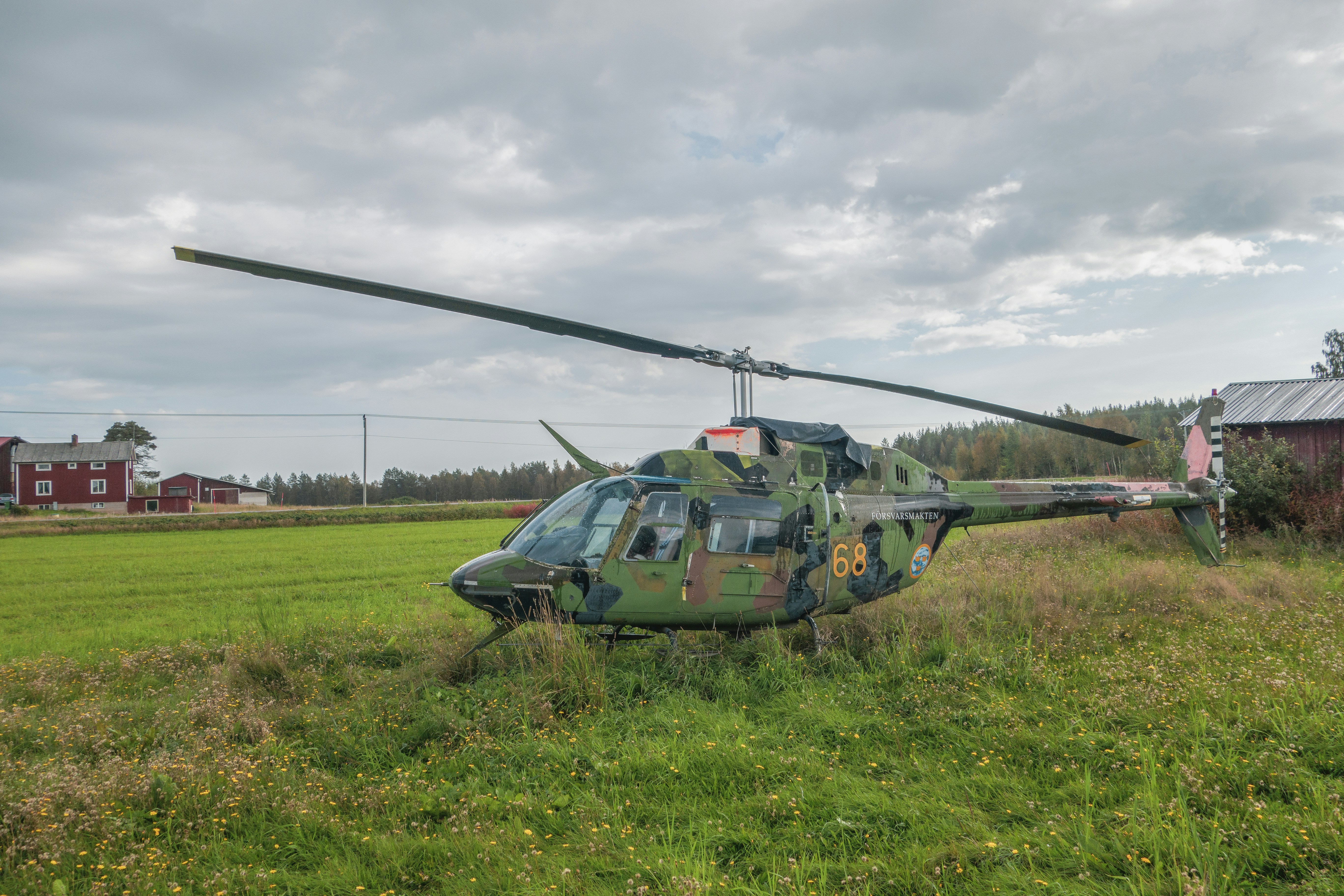 un elicottero seduto in un campo vicino a un fienile