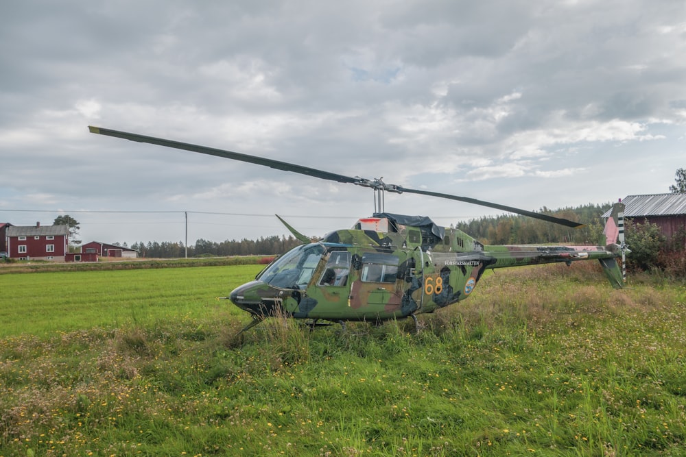a helicopter sitting in a field next to a barn