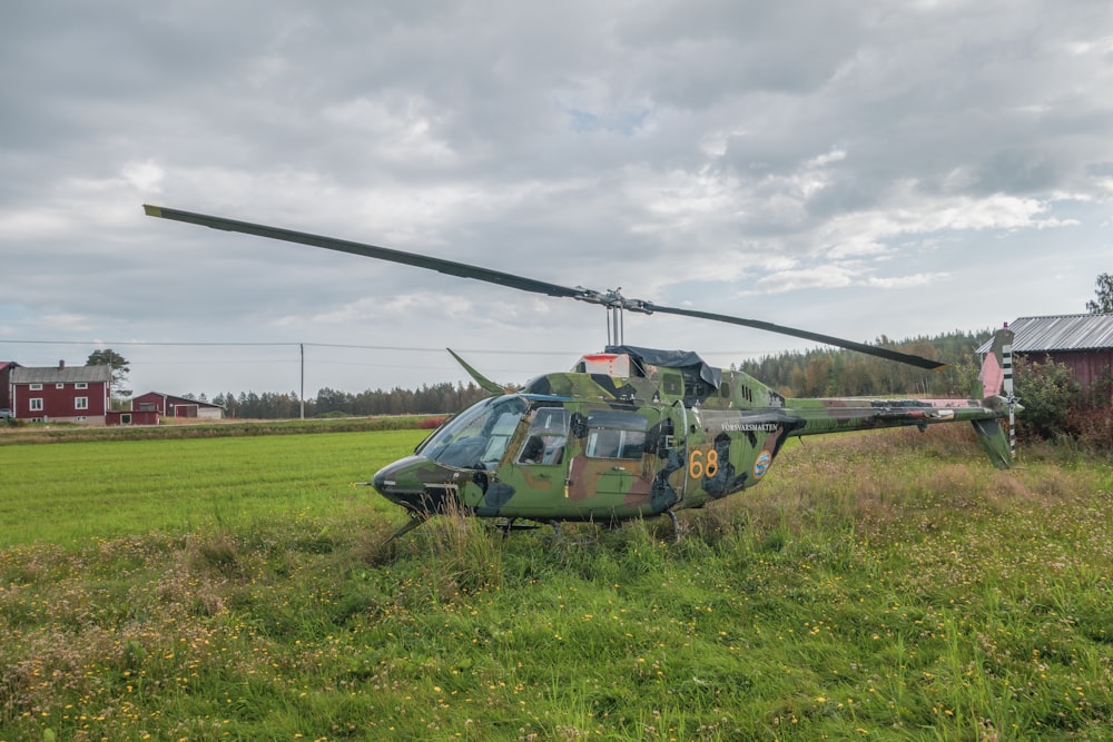 um helicóptero sentado em um campo ao lado de um celeiro