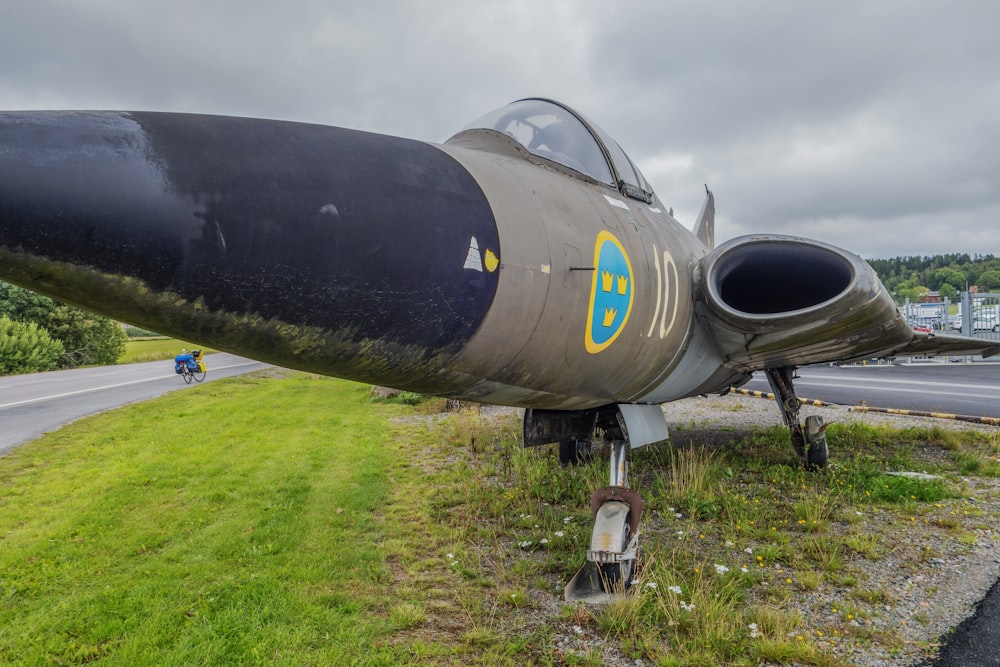 a fighter jet sitting on top of a lush green field