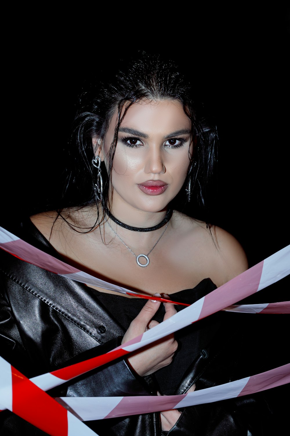 a woman in a leather jacket holding a red and white ribbon