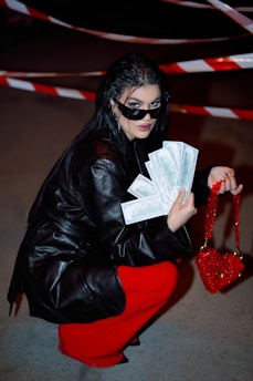 a woman in a black leather jacket and red pants