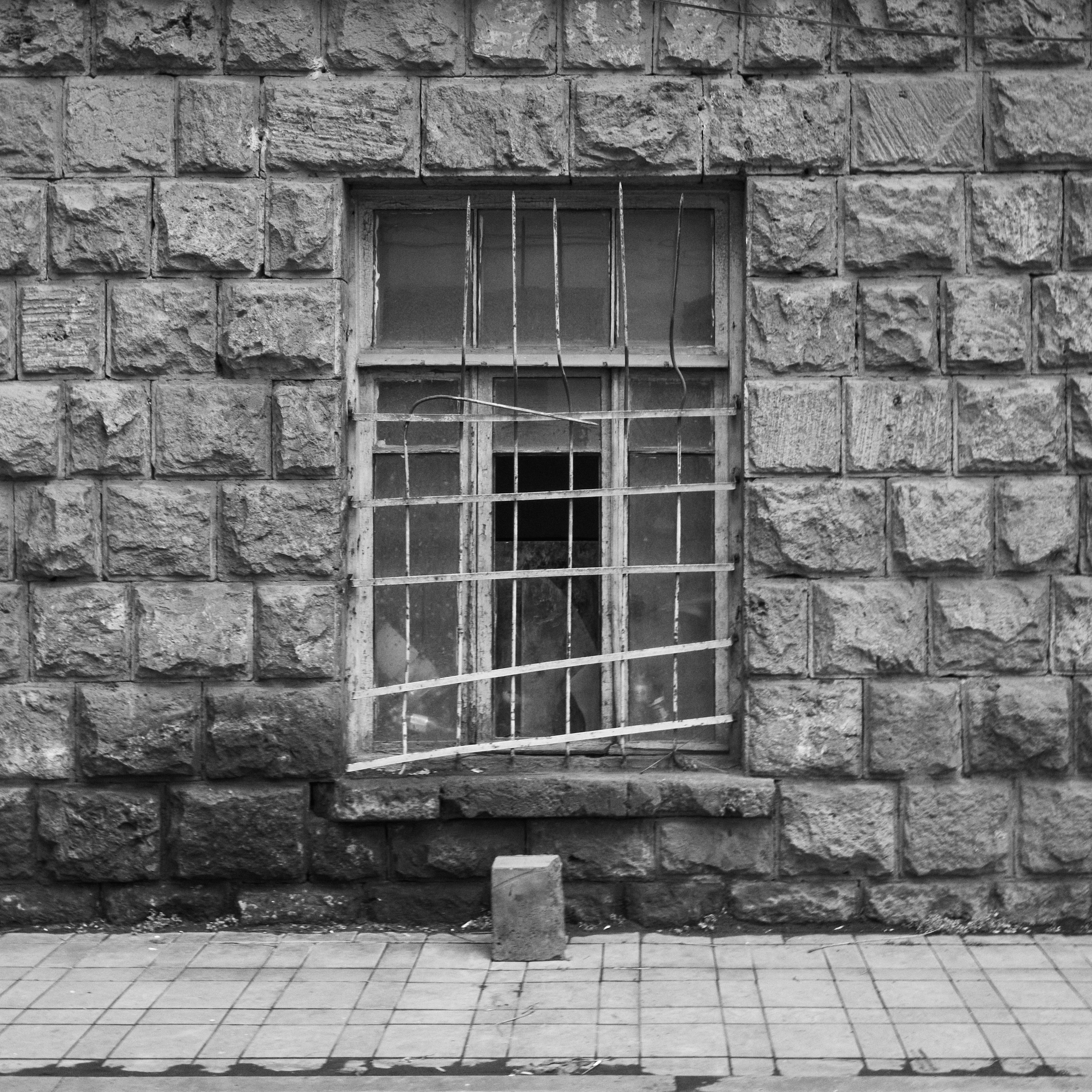 detainee: a black and white photo of a window on a brick wall