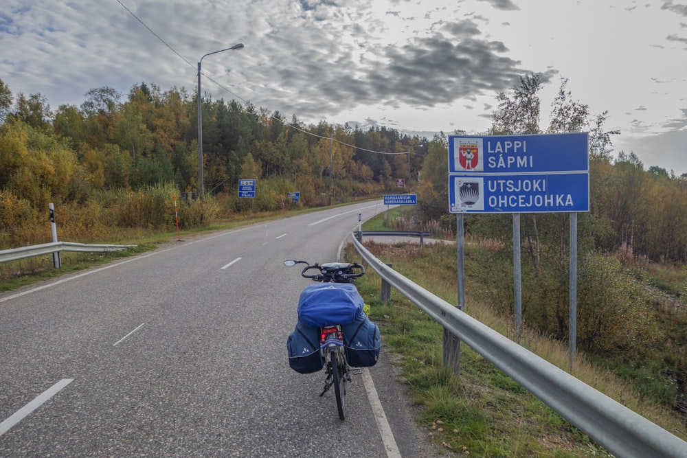 a bicycle parked on the side of a road next to a sign