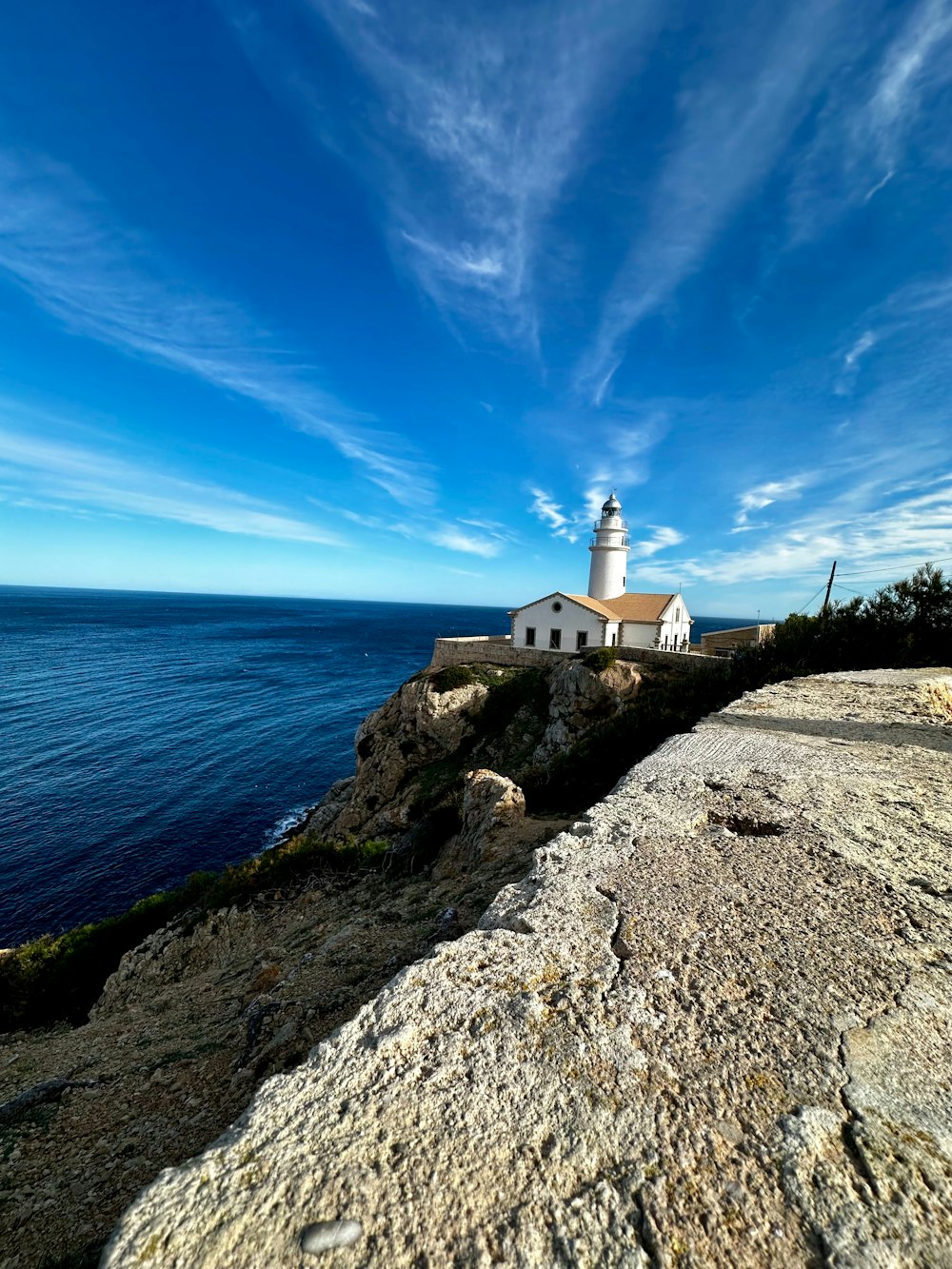 um farol em um penhasco rochoso com vista para o oceano