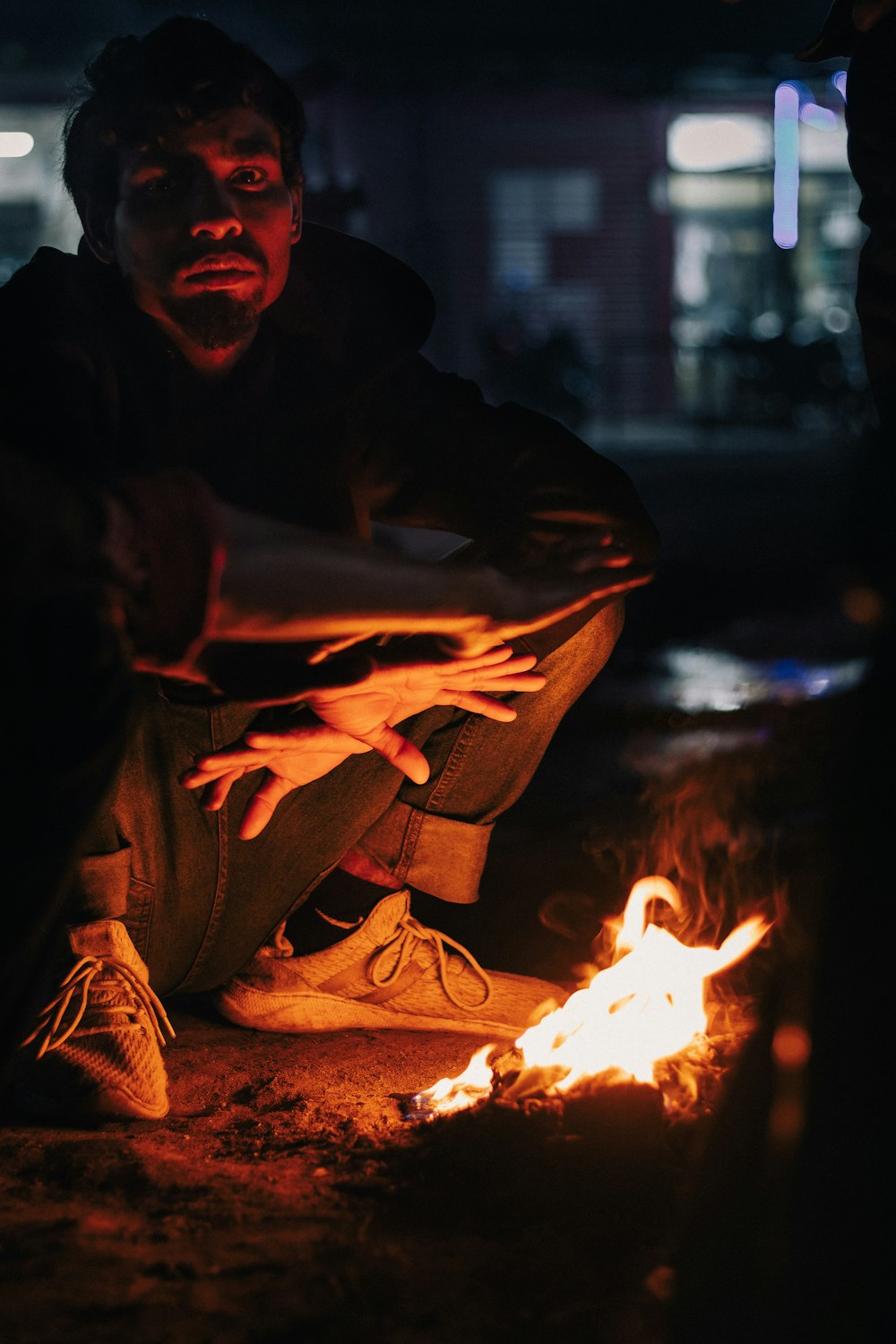 a man sitting on the ground next to a fire