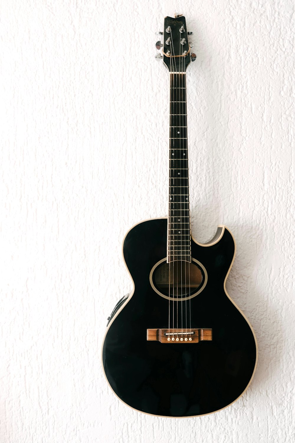a black acoustic guitar hanging on a wall