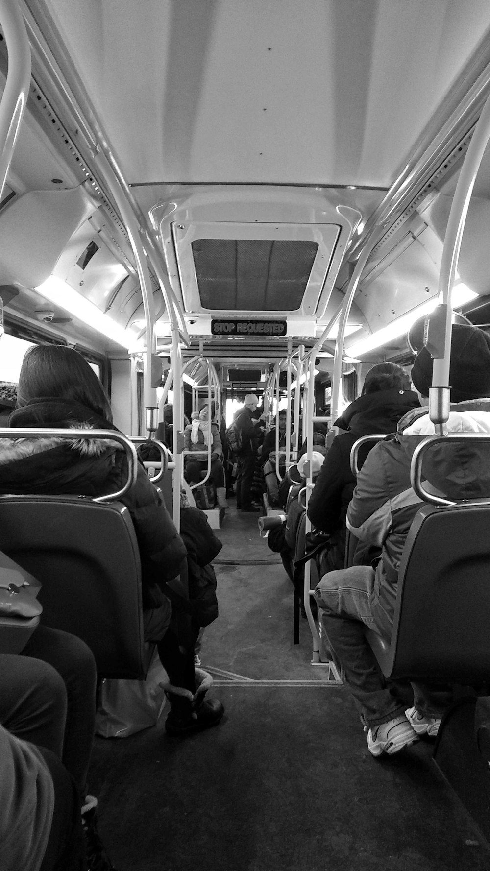 a black and white photo of people sitting on a bus