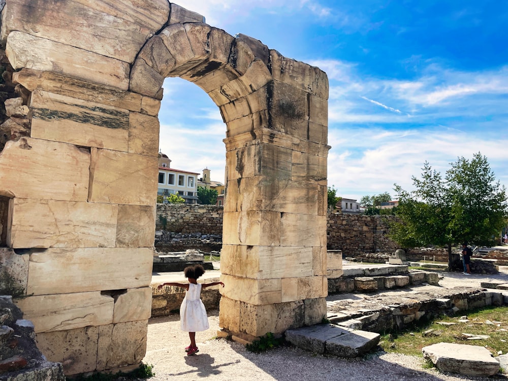 une femme debout devant une arche de pierre