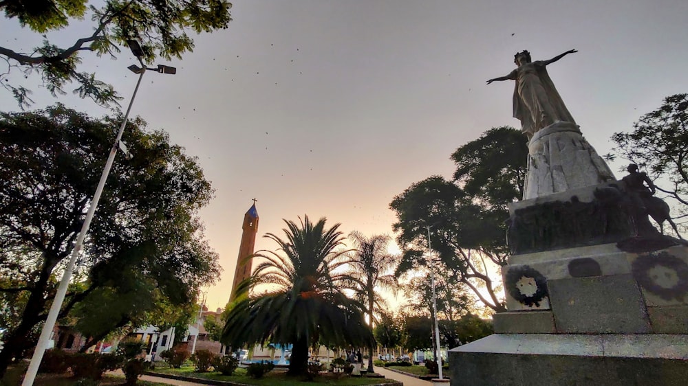 a statue in a park with trees in the background