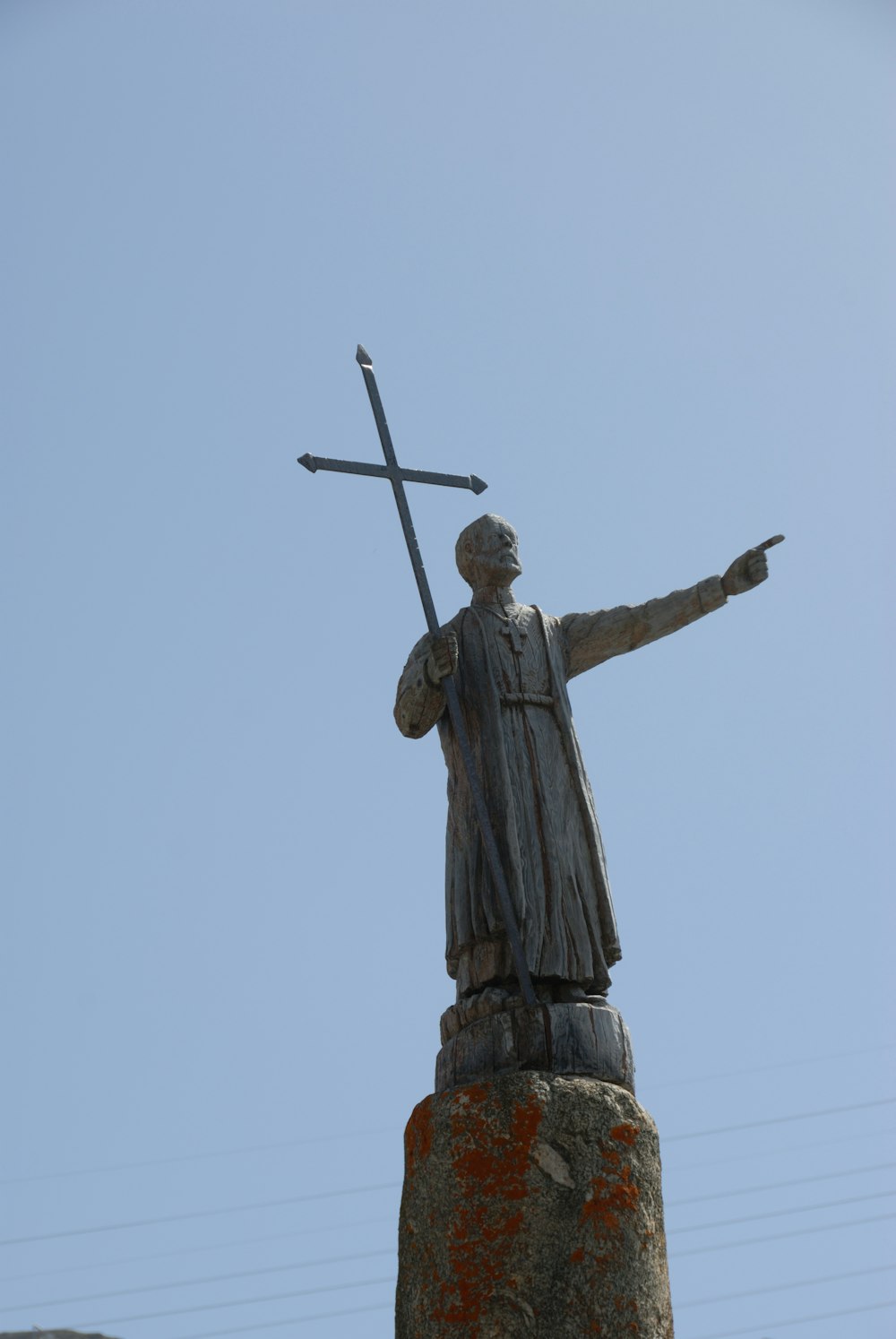 a statue of a man holding a cross on top of a rock