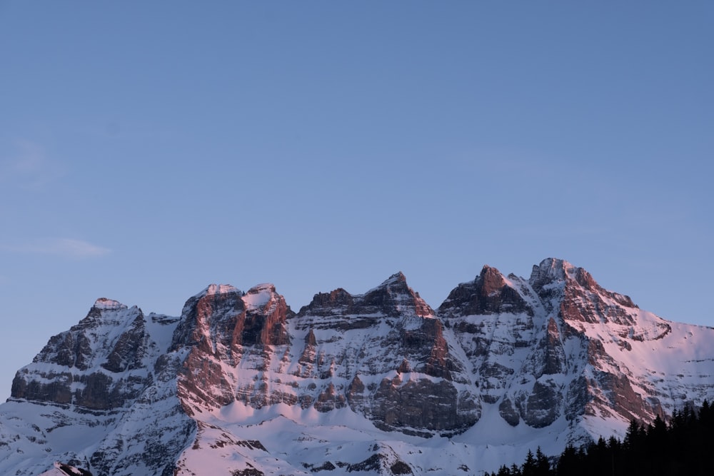 a snow covered mountain range with a blue sky in the background