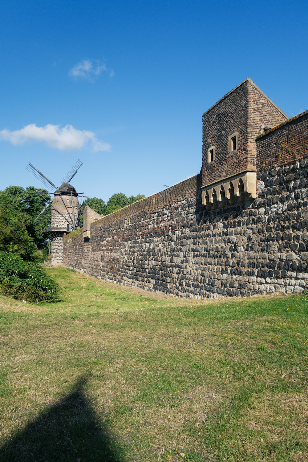 an old brick wall with a windmill in the background