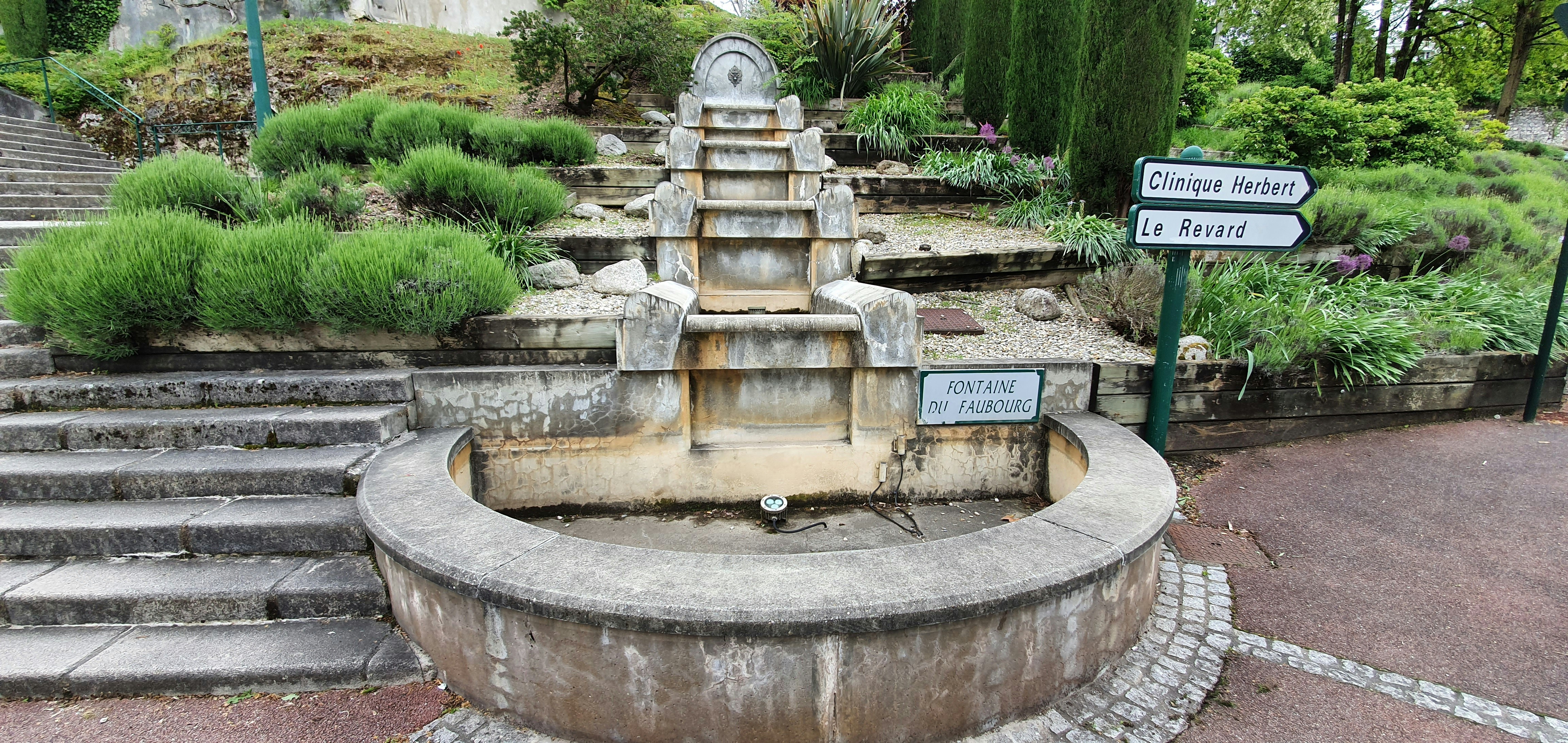 a stone fountain in a park with steps leading up to it