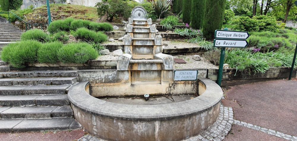 a stone fountain in a park with steps leading up to it