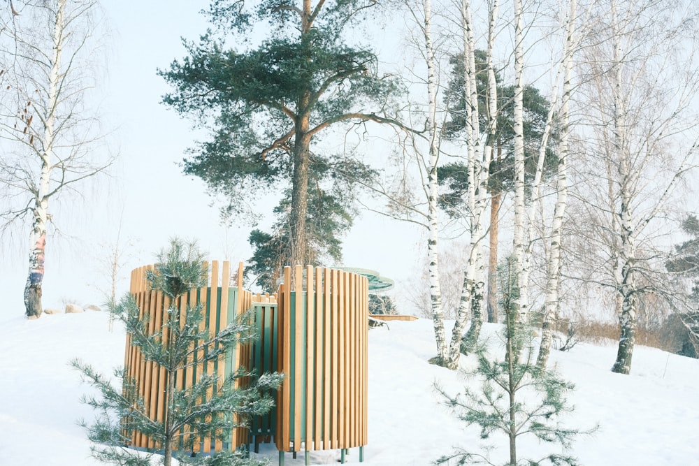 a wooden structure surrounded by trees in the snow