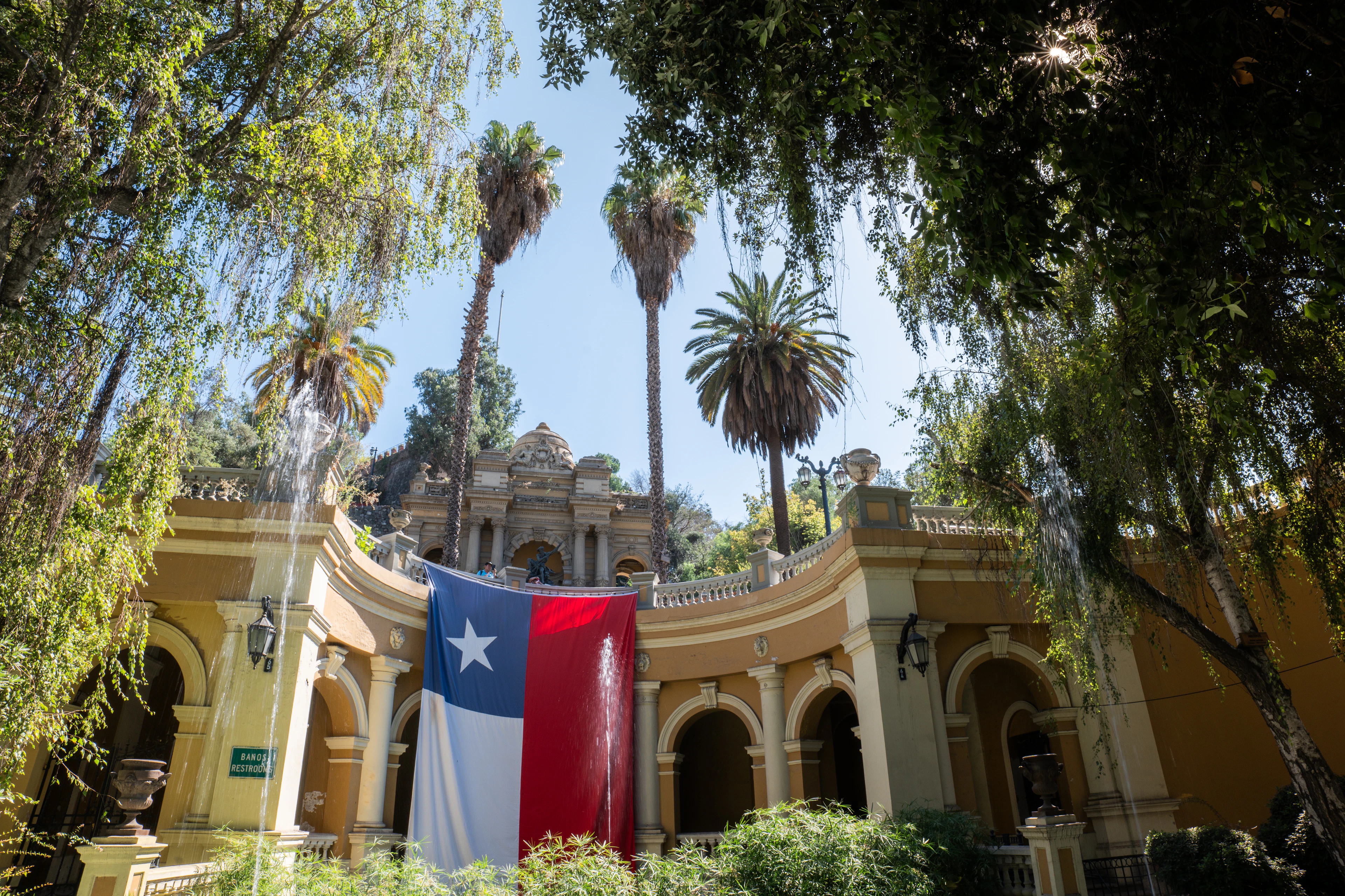 A Chilean flag hangs between colonial arches and palm trees on Cerro Santa Lucia in Santiago.