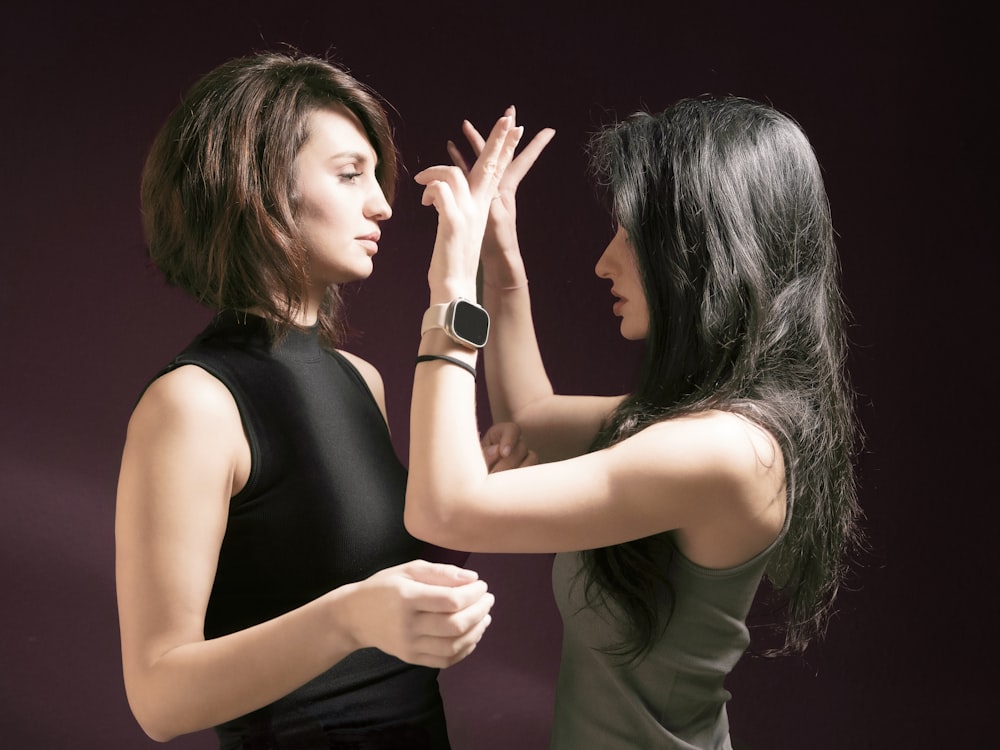 two women standing next to each other with their hands together