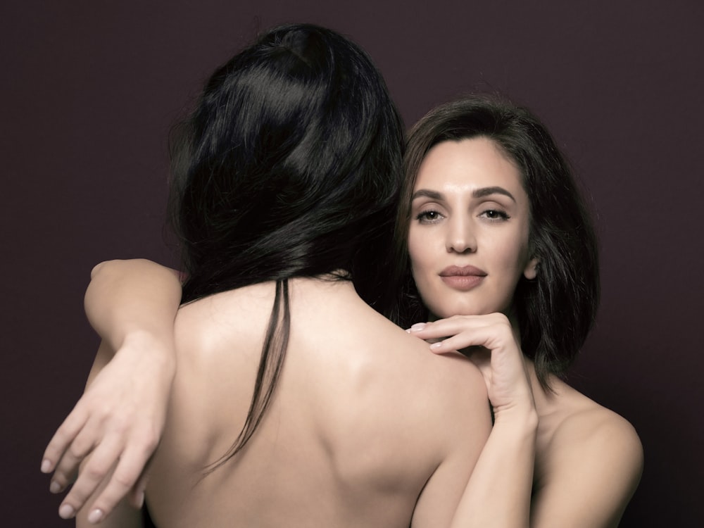 a woman is hugging another woman's back
