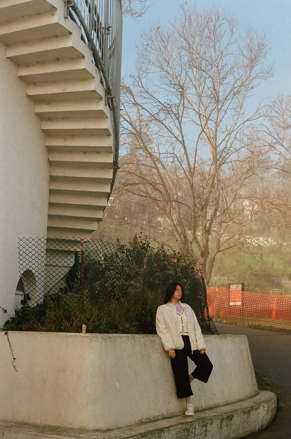 a man sitting on a wall next to a spiral staircase