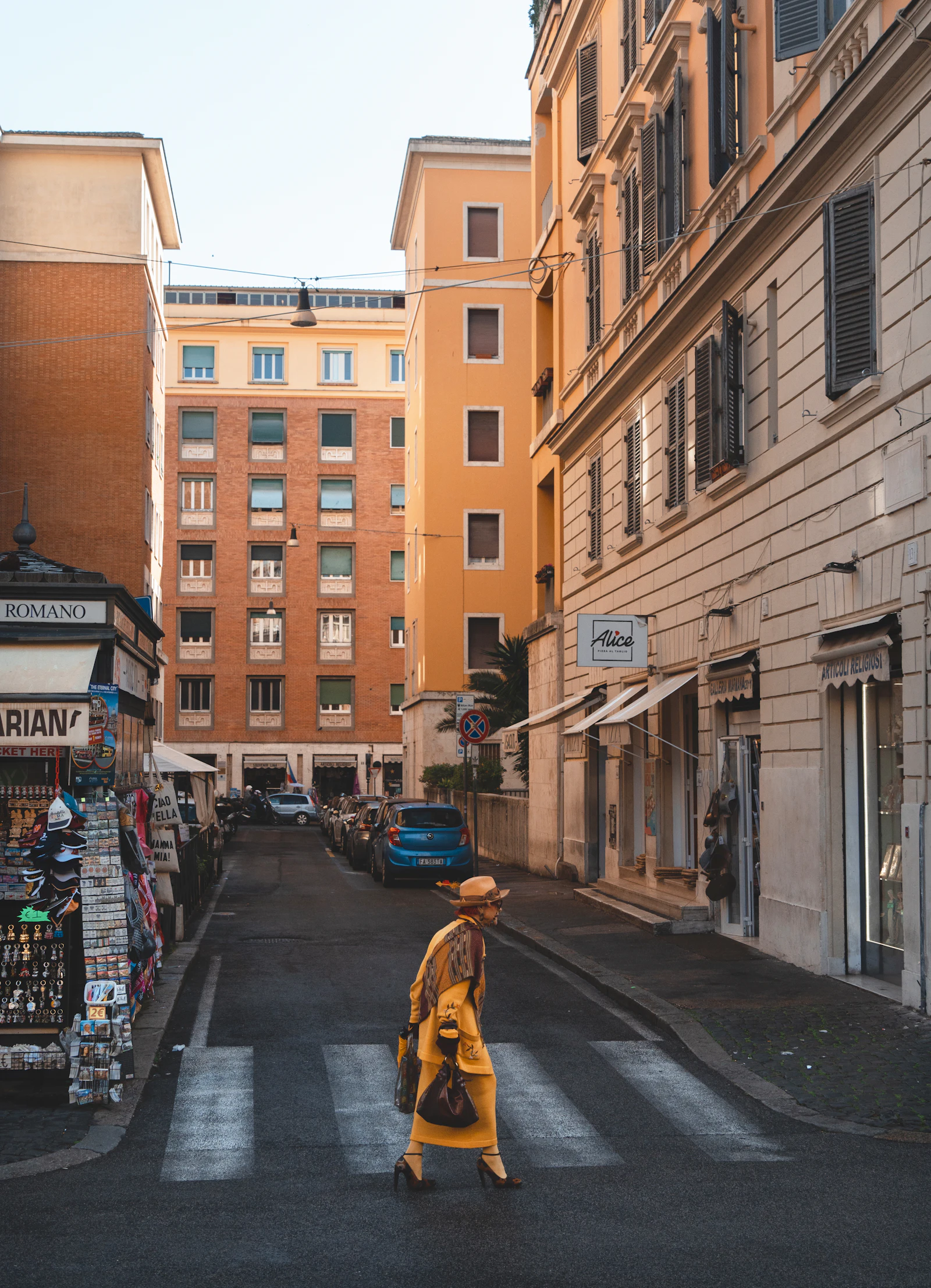 Woman crossing a narrow street lined with old buildings in Rome