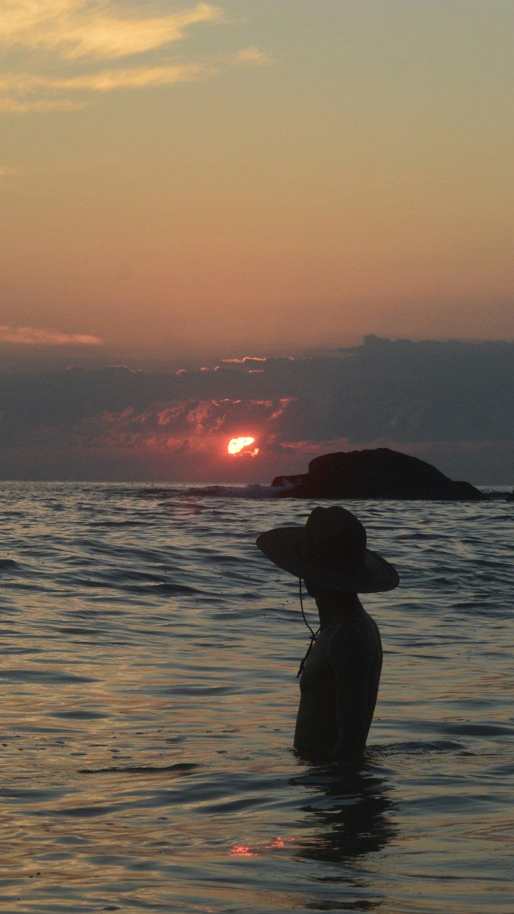 eine Person, die bei Sonnenuntergang im Wasser steht
