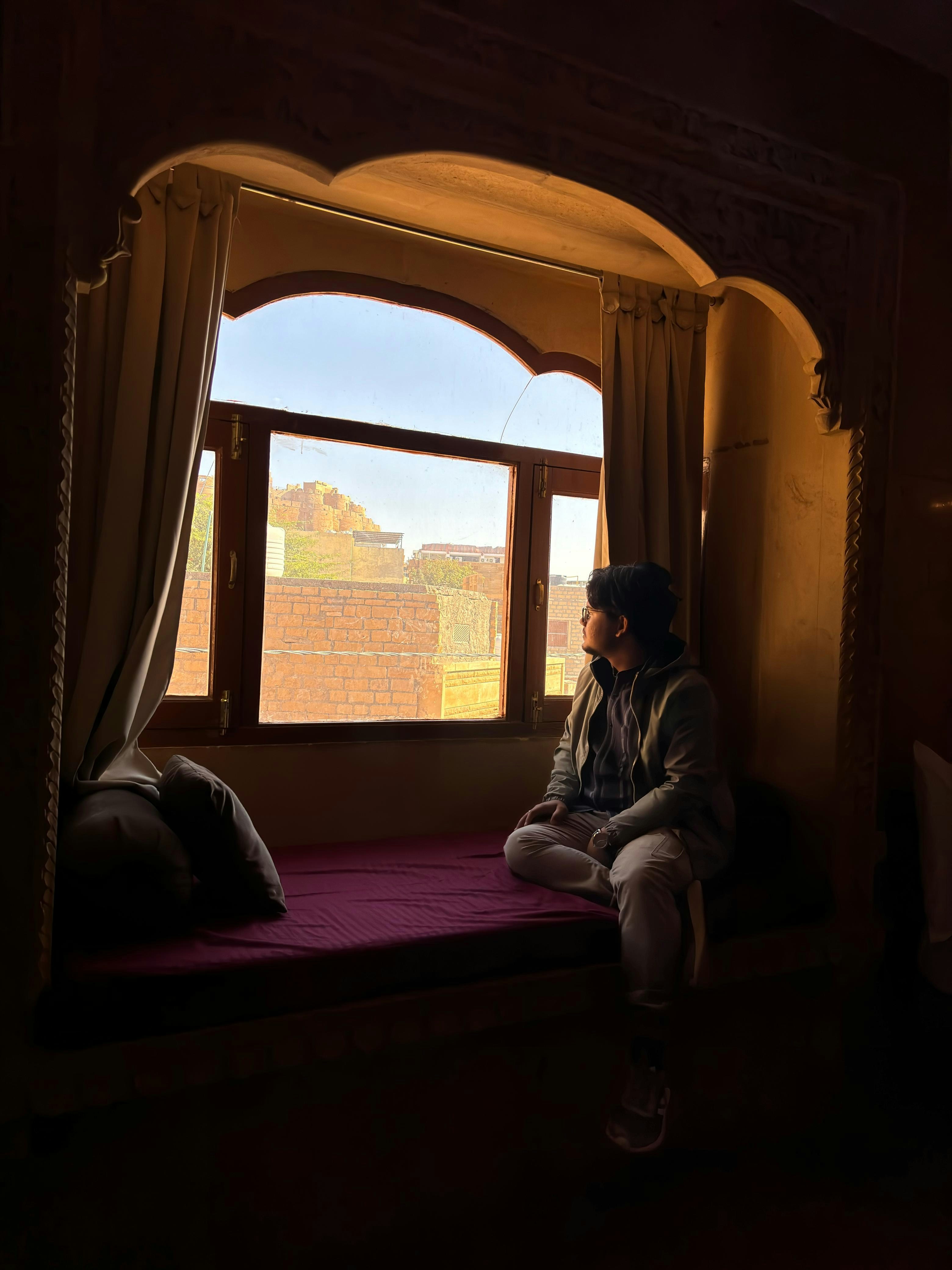 ベッドに座って窓の外を眺めている人