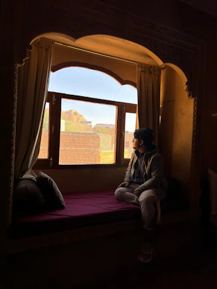 a person sitting on a bed looking out a window