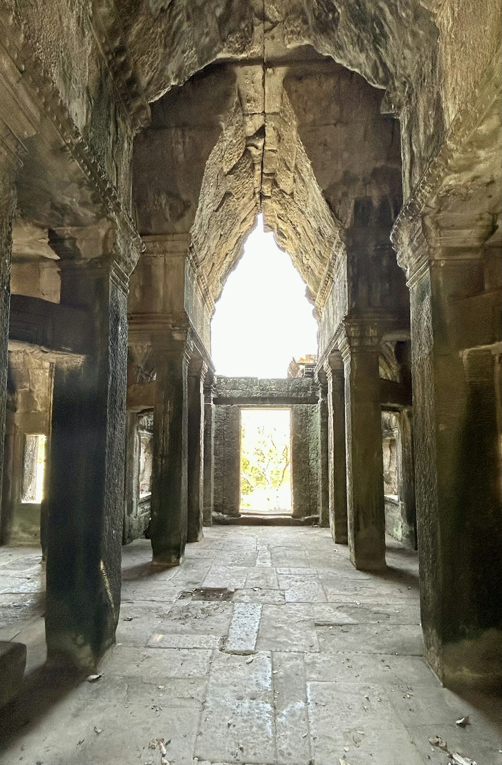 a long hallway with stone pillars and a window