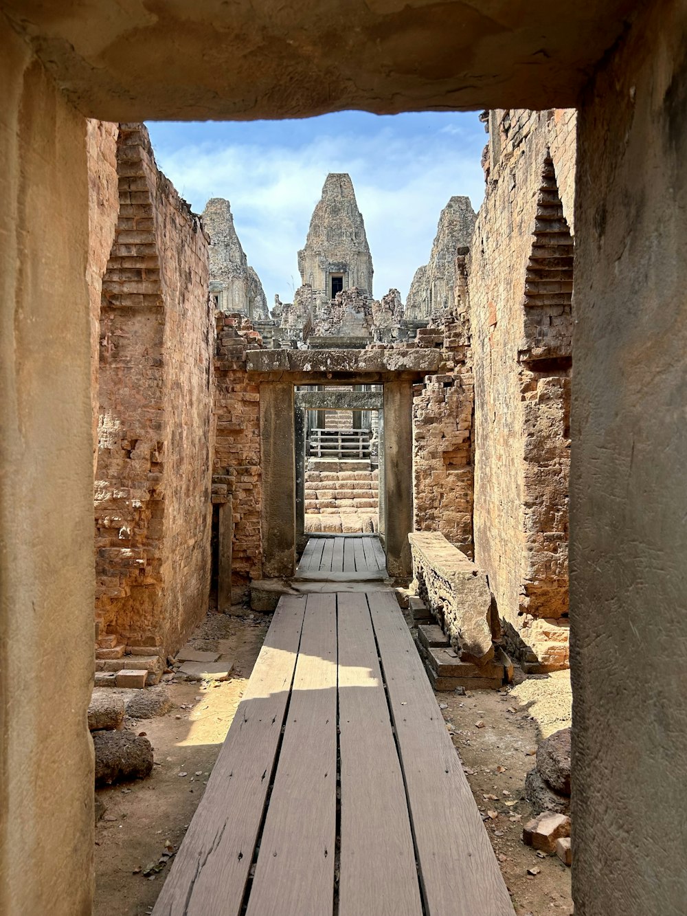 a wooden walkway between two stone buildings