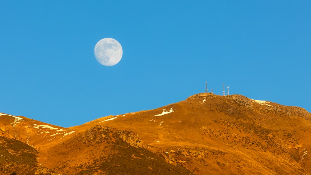 a view of a mountain with a half moon in the sky