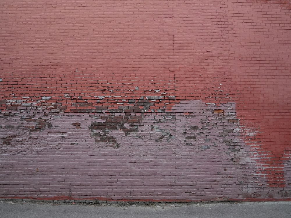 a red brick wall with peeling paint on it