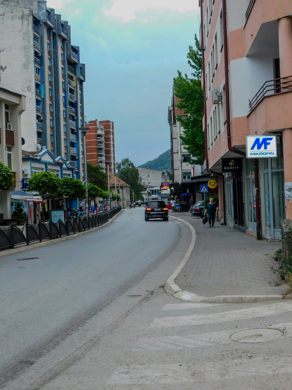 a car driving down a street next to tall buildings