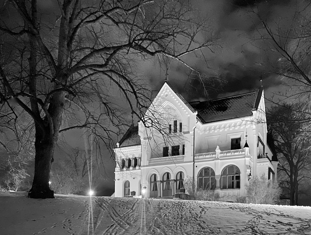 una gran casa blanca sentada en la cima de una colina cubierta de nieve