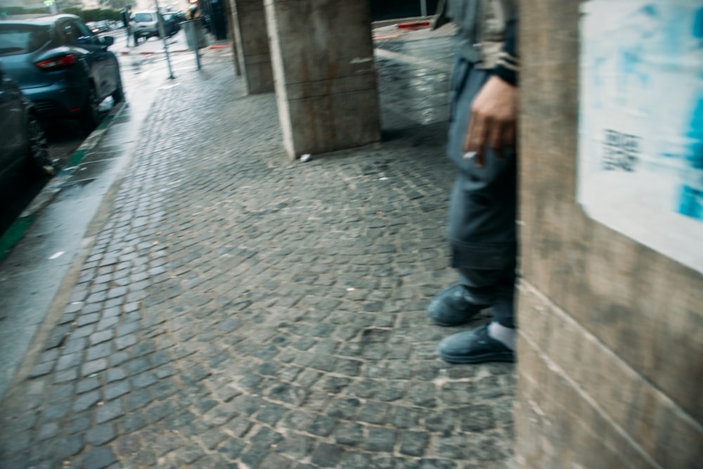 a person standing on a brick sidewalk next to a building