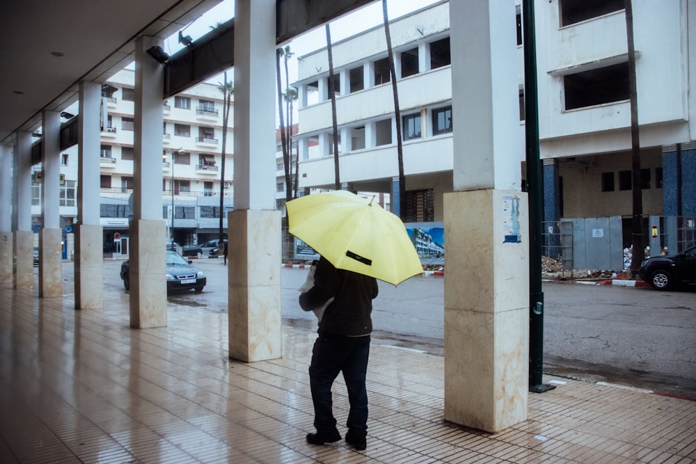 a person holding a yellow umbrella on a sidewalk