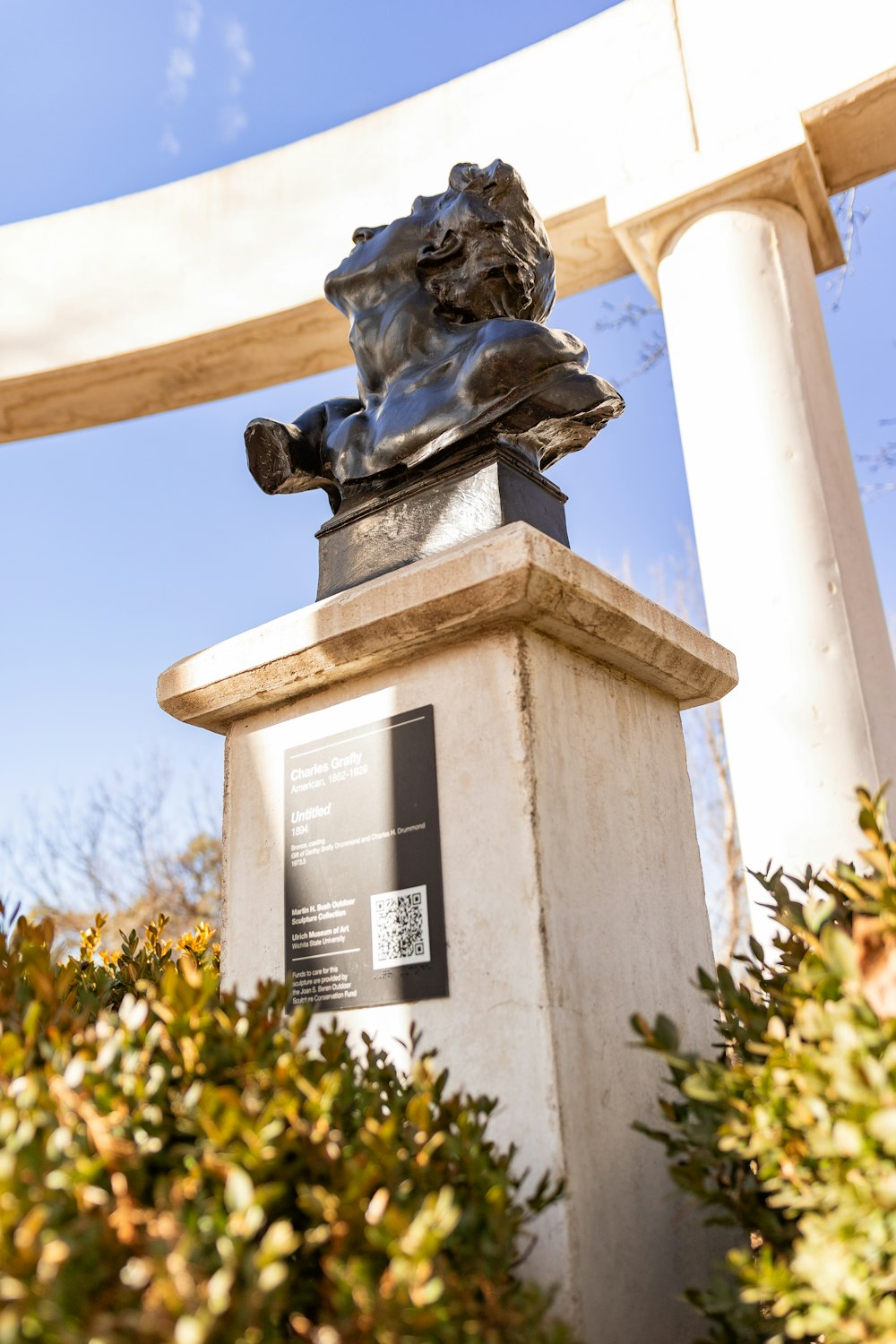 a statue of a man sitting on top of a white pedestal