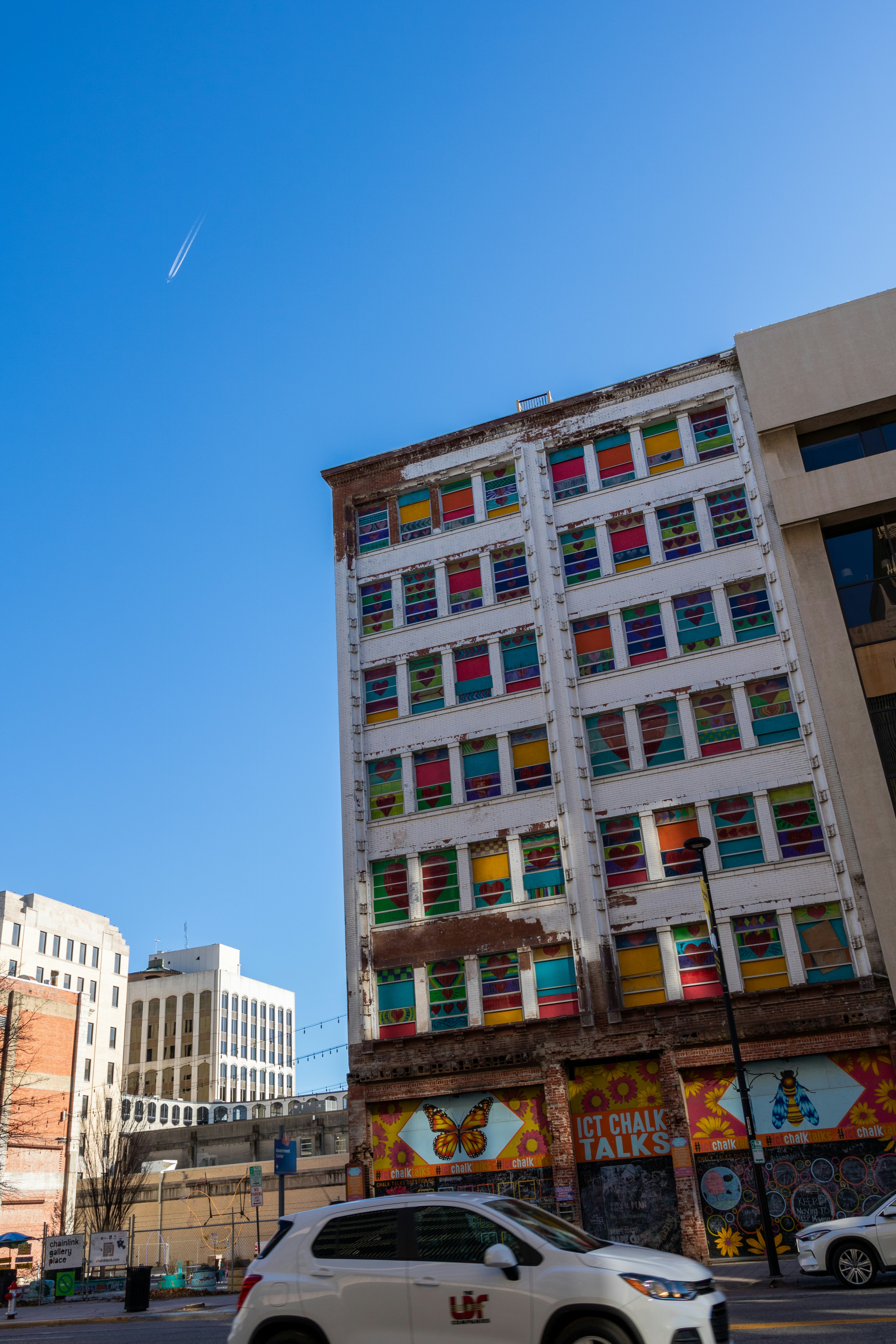 a white car driving down a street next to tall buildings