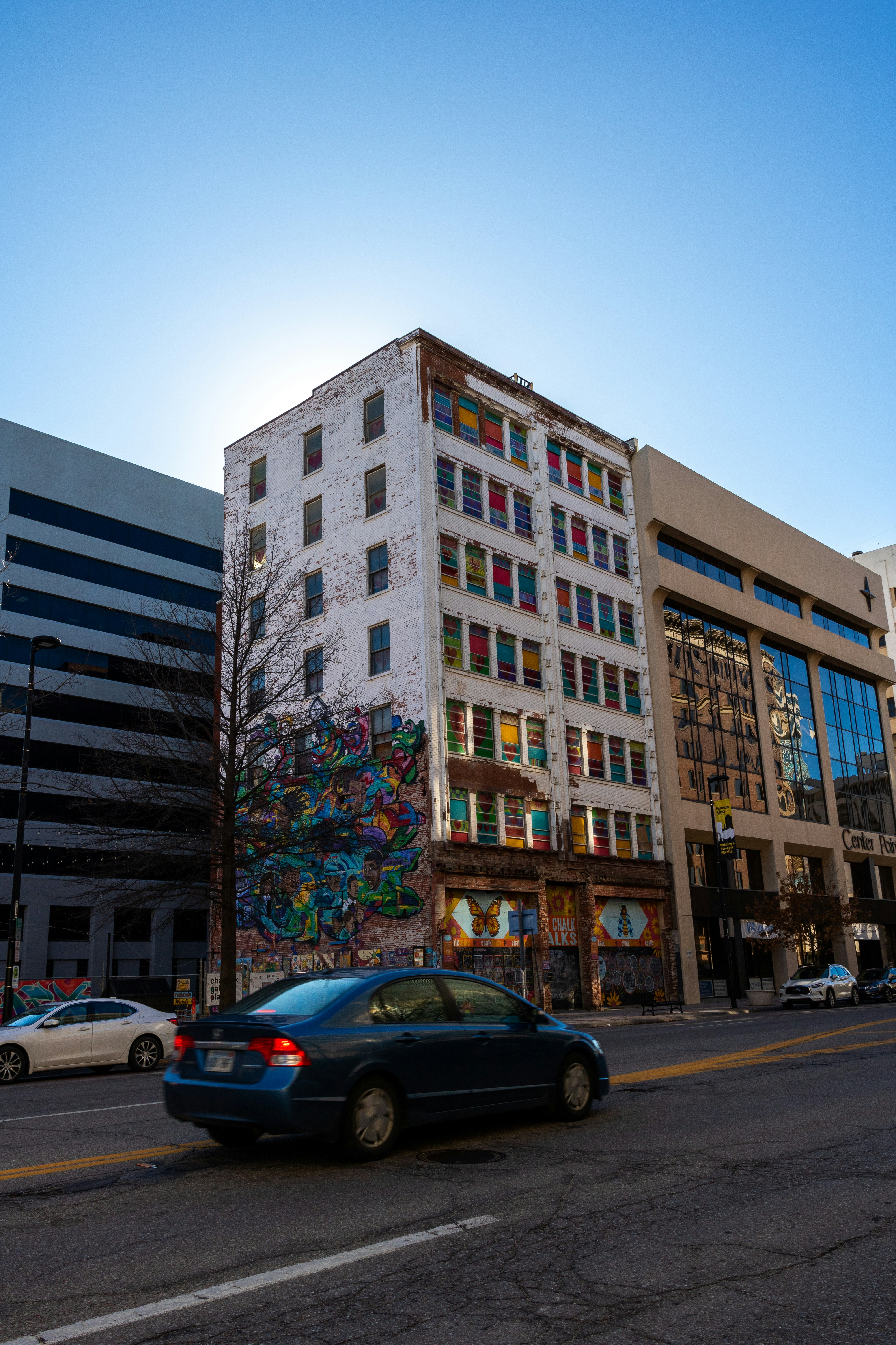 a blue car driving down a street next to tall buildings