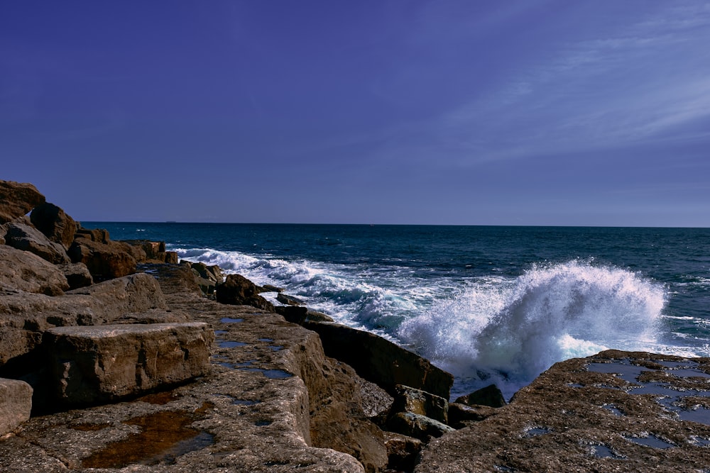 a wave crashes against the rocks at the ocean