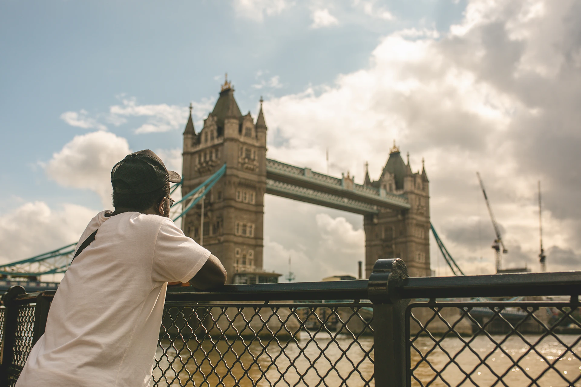 a man standing next to a fence near a river