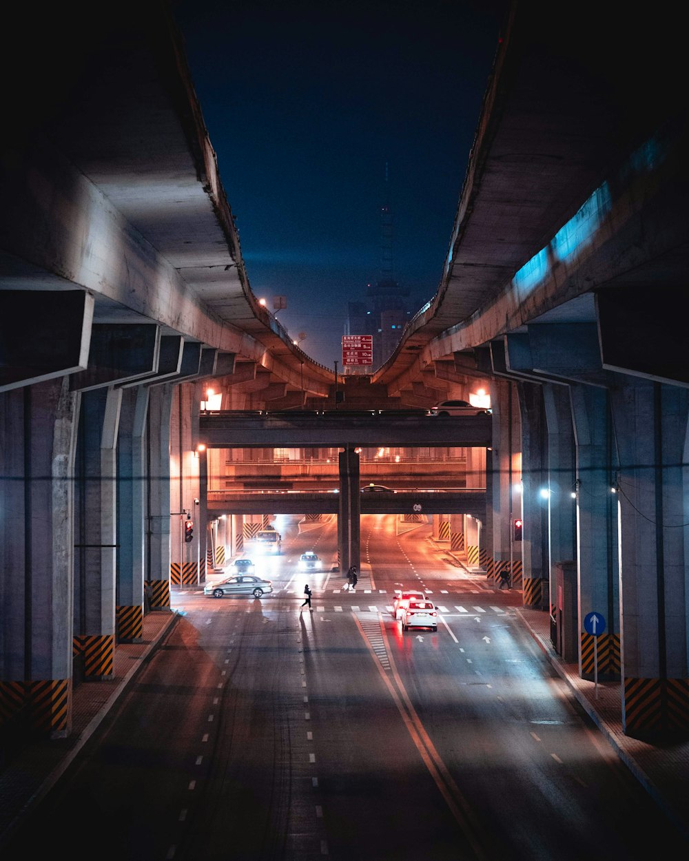 a city street at night with cars driving under a bridge